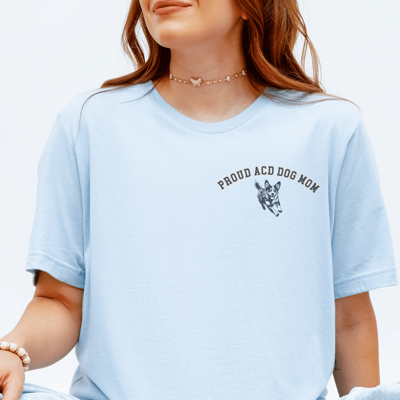 Person wearing a light blue t-shirt with text and graphics, sitting on a checkered floor.