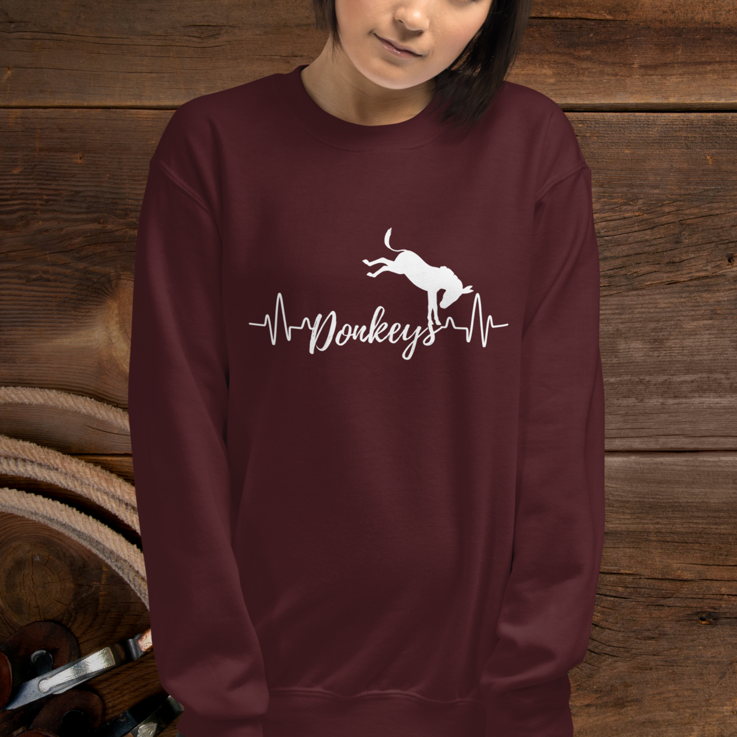Maroon crew neck sweatshirt with a heart beat design with the word Donkeys in the middle of the heartbeat, with a silhouette of a bucking donkey above it.