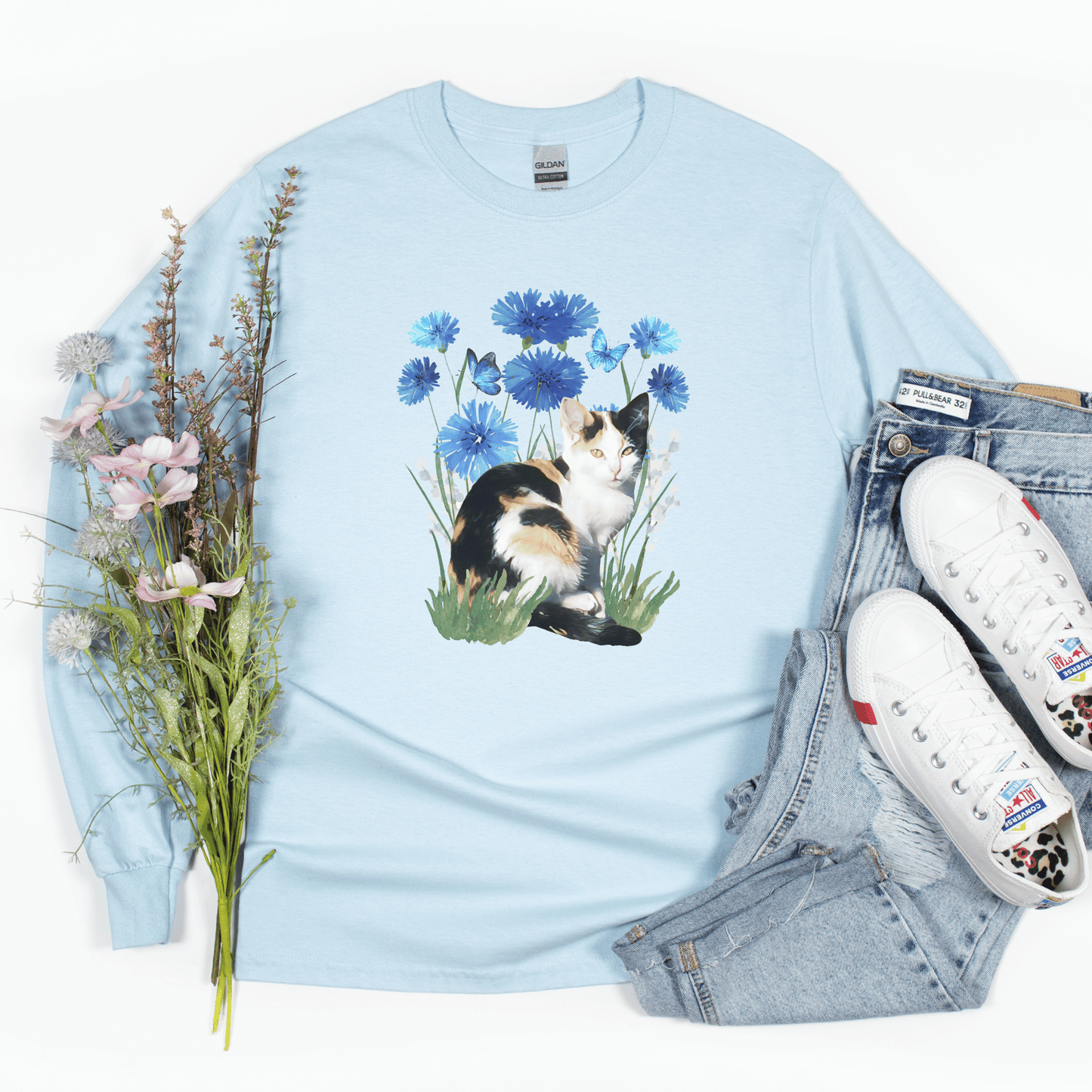 Featuring a delightful blue flower design and an adorable calico cat, this t-shirt is both stylish and comfortable. Made with high-quality materials,