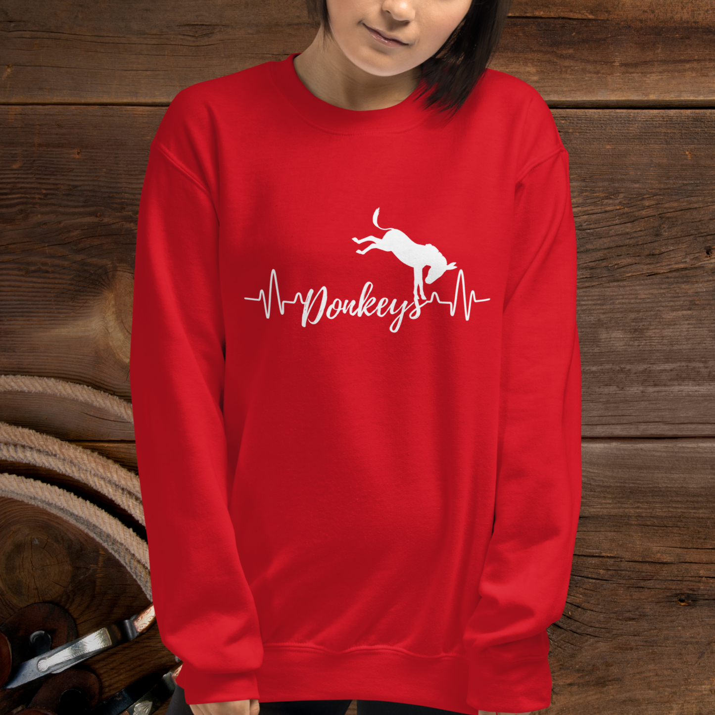 Red crew neck sweatshirt with a heart beat design with the word Donkeys in the middle of the heartbeat, with a silhouette of a bucking donkey above it.