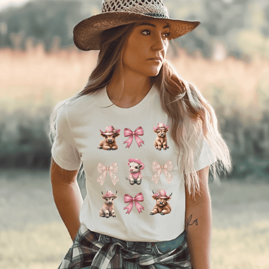 Coquette style design that includes cute highland cow calves and pink ribbions on a high quality t-shirt.