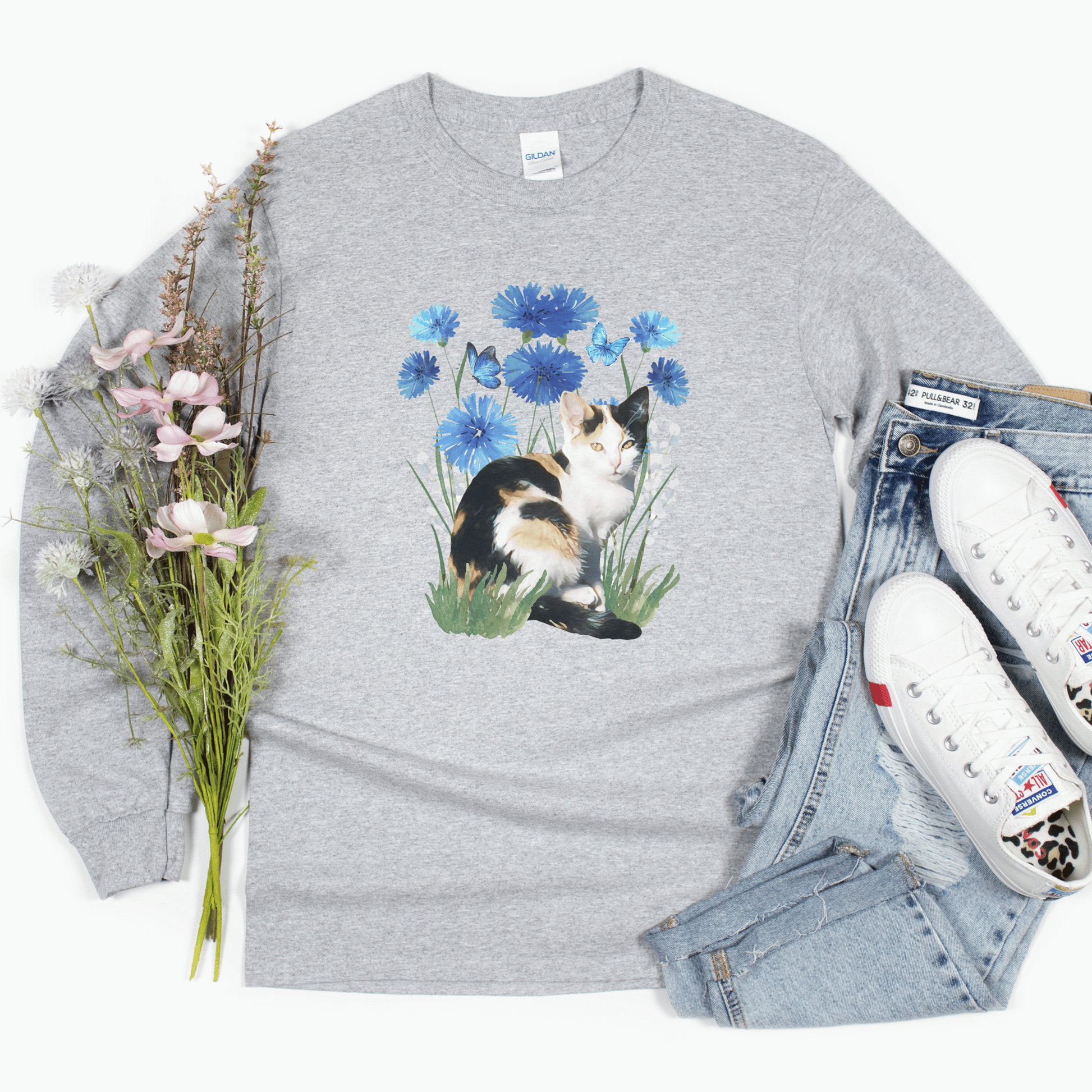 Featuring a delightful blue flower design and an adorable calico cat, this t-shirt is both stylish and comfortable. Made with high-quality materials,