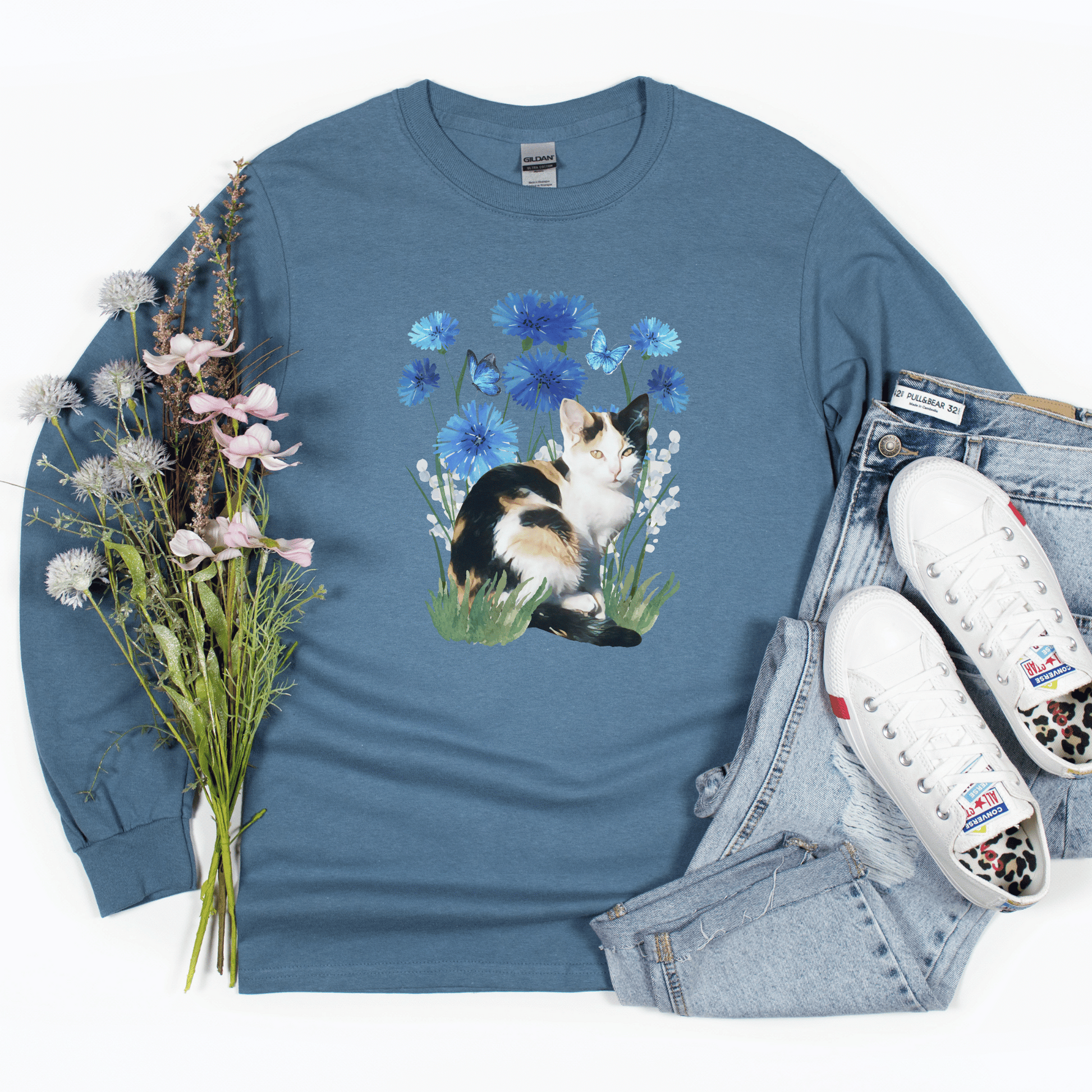 Featuring a delightful blue flower design and an adorable calico cat, this t-shirt is both stylish and comfortable. Made with high-quality materials,